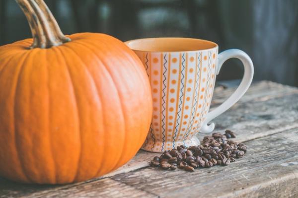 Pumpkin sitting by a coffee cup